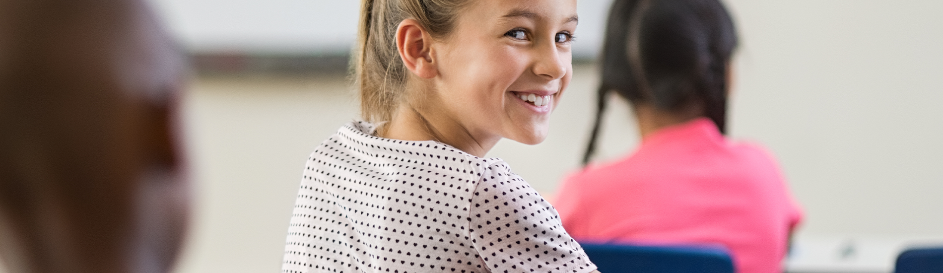 Flicka i klassrum vänder sig om mot kameran