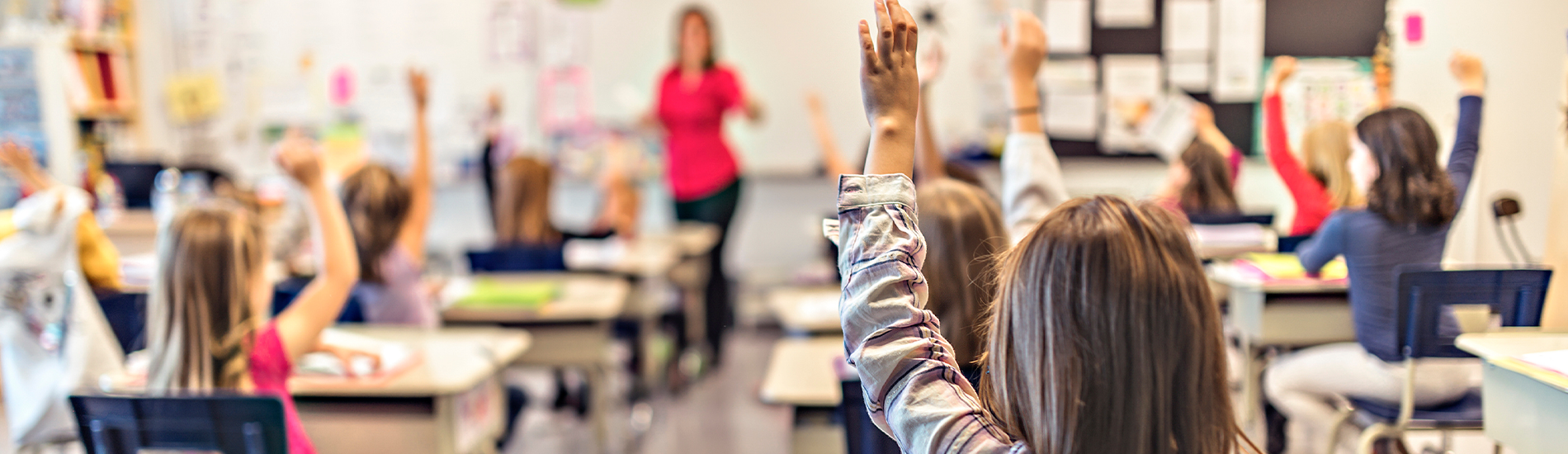 Elever i ett klassrum som räcker upp händerna